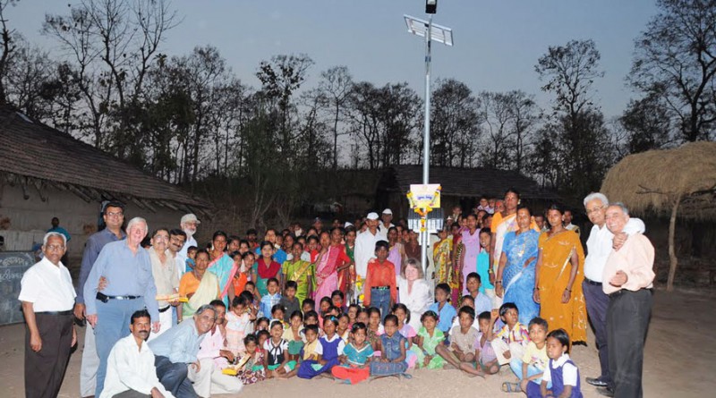 Rotarians and villagers standing under a newly installed solar street lamp.