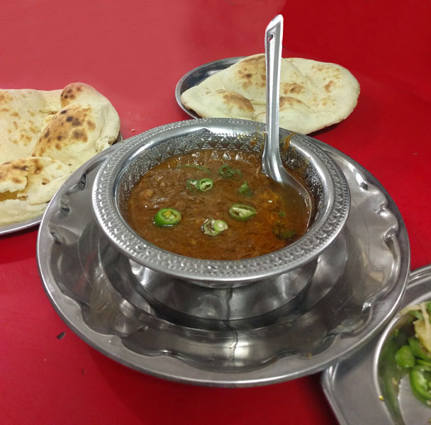 Nihari garnished with fried onion and green chillies.