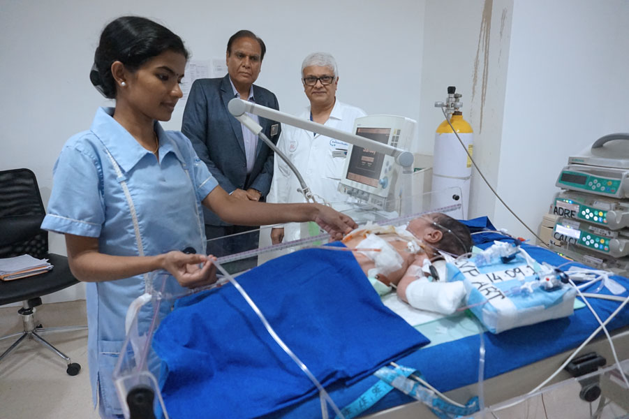 Dr Suresh Rao, accompanied by D 3141 DG Gopal Mandhania examines an infant after surgery.