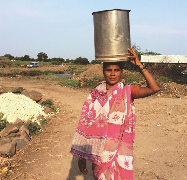 A woman carries water drawn from the hand-pump installed near the water-pits.