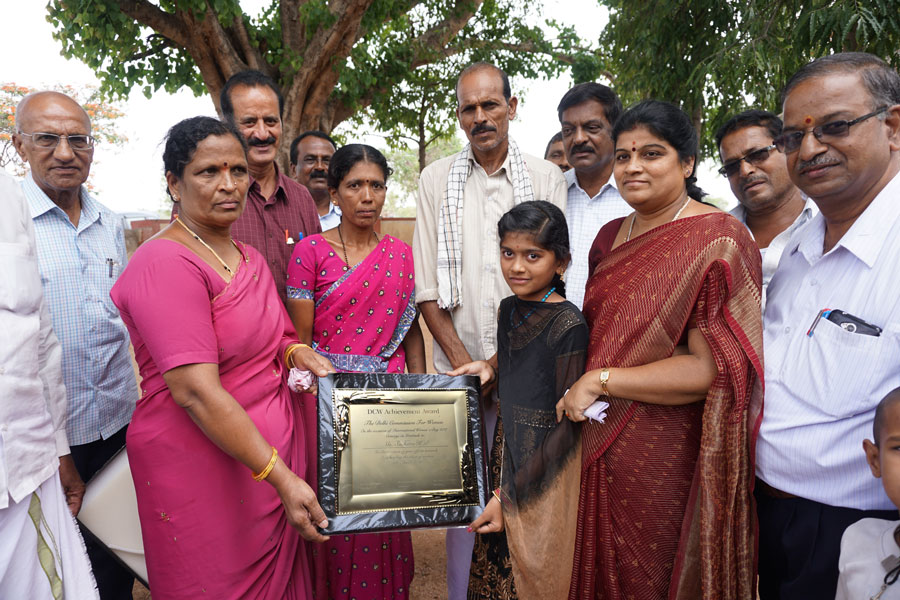 Suchitra displays the DCW Award in the presence of her parents Prabhu and Geetha (centre), Z P member Rathnamma, Rtn C V Srinivas Shetty, Club President G Guruswamy, Rtn Prabhakar, Gram Panchayat President Nagalambika and headmaster Shivakumar.