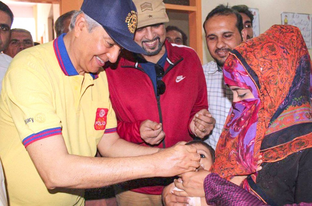 TRF Trustee Aziz Memon administering polio drops to a child.