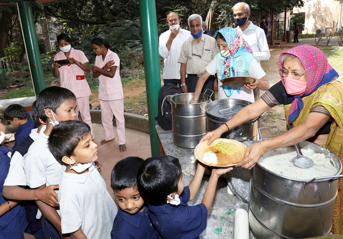 Volunteers Thara and Chandrakala from the Sri Sai Spiritual Centre serve food to the children.
