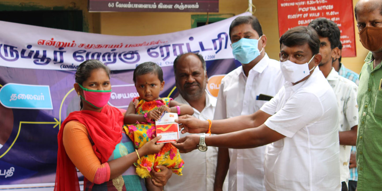 Club president V Raghupathy hands over a savings certificate to a girl child in the presence of club members Balasubramaniam and Nataraj.