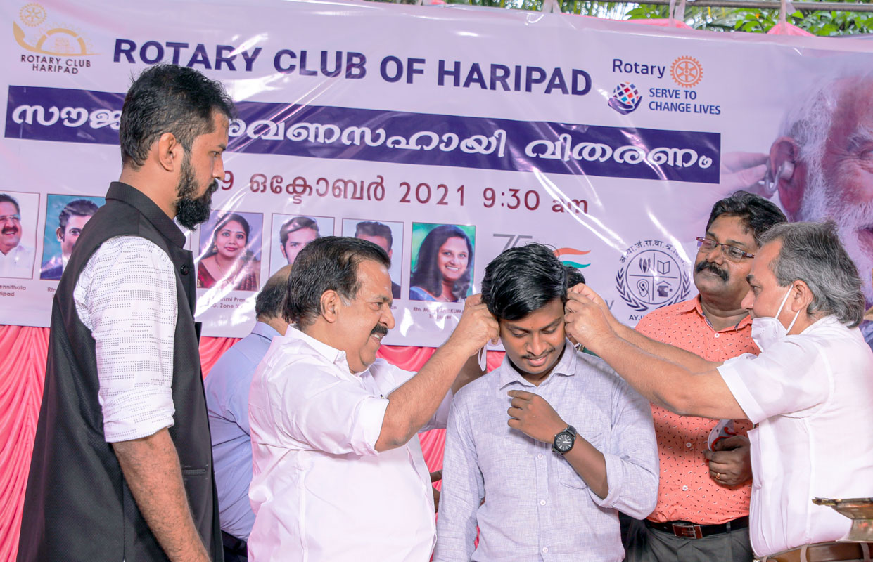 Haripad MLA Ramesh Chennithala fits a hearing aid on a beneficiary. On the left is club president Manu Mohan. 