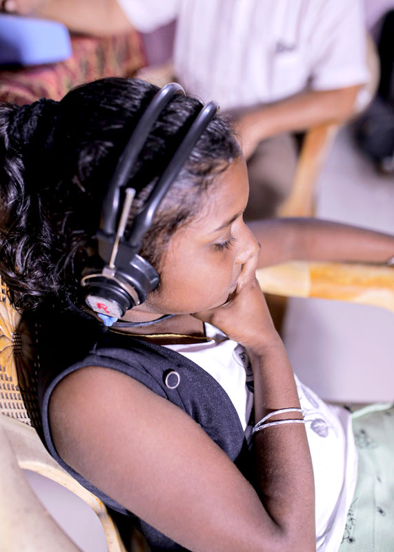  A little girl listens to music on her headphones after having a hearing aid fitted. 