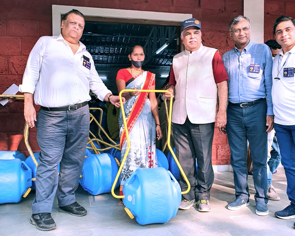 DG Rajendra Agarwal (third from L) gives a waterwheel to a woman in a village. Rotary Water Projects Avenue Chair Amrish Daftary is to his left. 