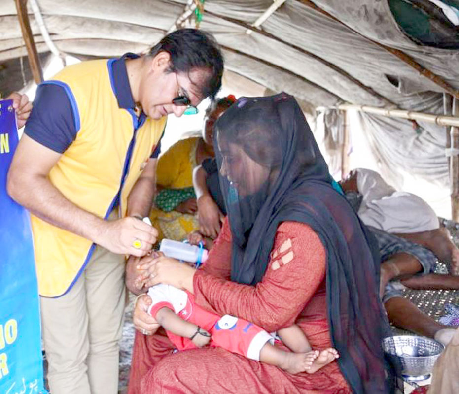 RID 3272 DG Saifullah Ejaz giving polio drops to a child. 