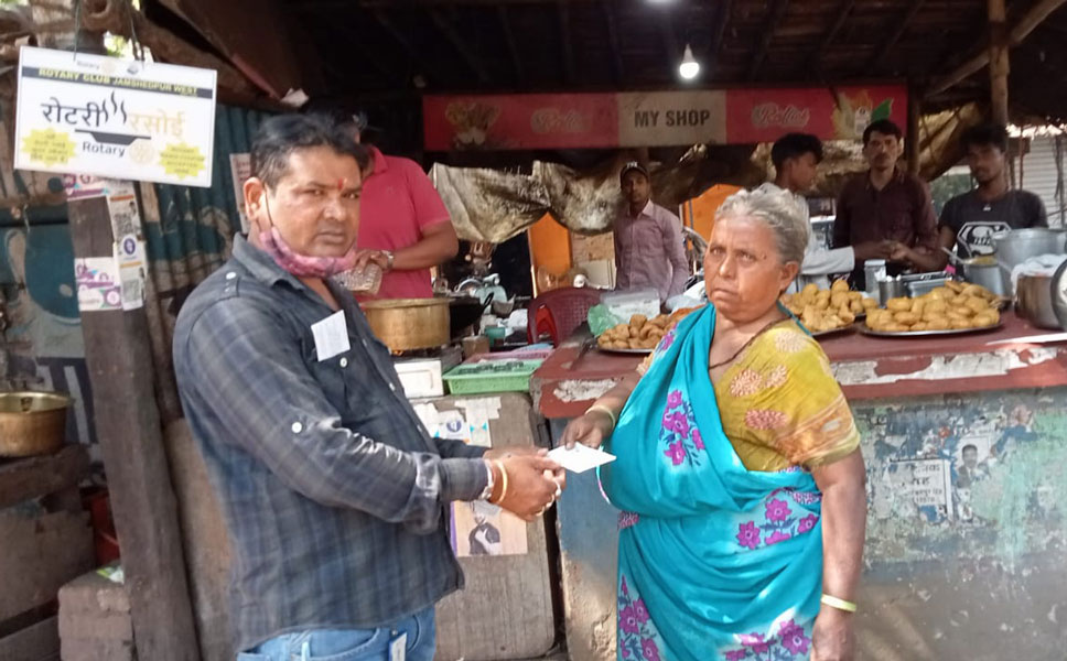 Satyajeet Dey, a non-Rotarian, gives a food ­coupon to an elderly at a Rotary Rasoi food cart.