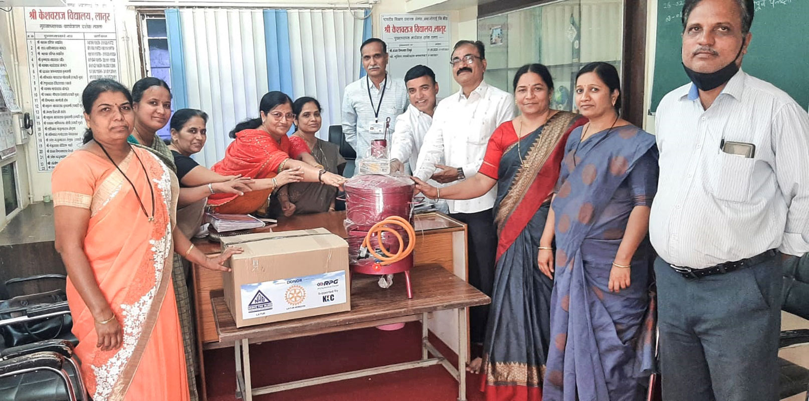 RC Latur Midtown president Satish Kadel and project chair Vishal Ayachit give an incinerator and a carton of sanitary pads to a school.
