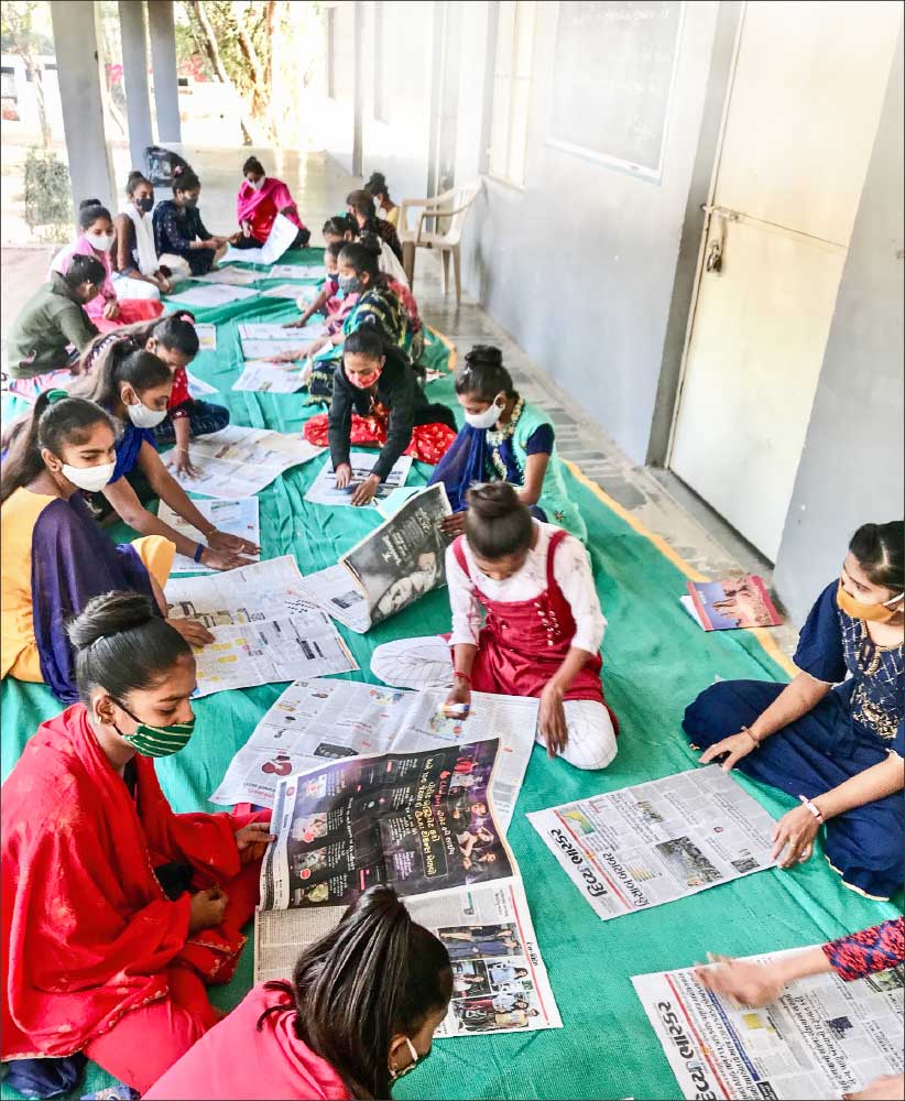 Girls learn to make paper bags. 