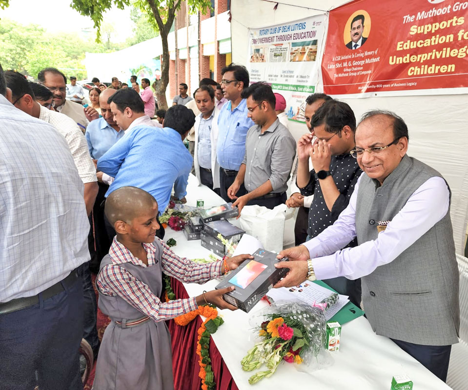 DG Ashok Kantoor giving a tablet to a student.