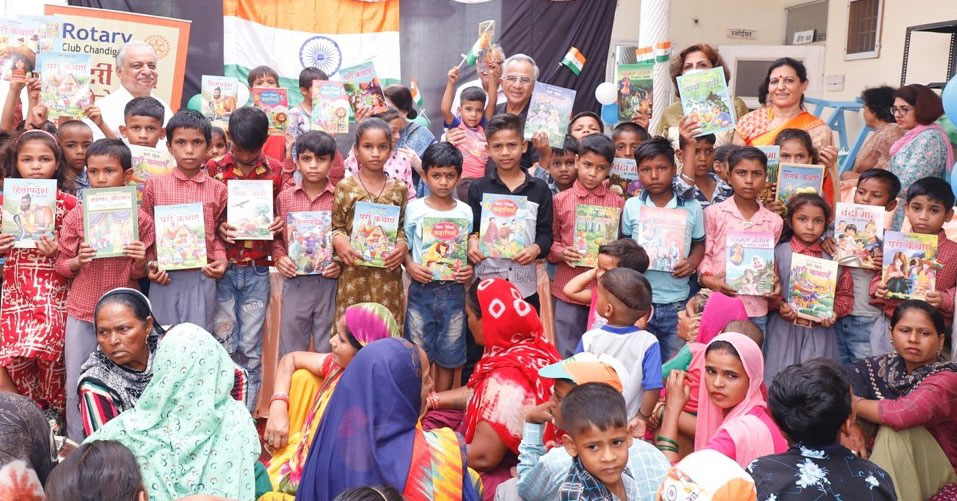 Above: PRIP Rajendra Saboo (back row, centre) and PDG Praveen Goyal (back row, left)  with club members after distributing story books to children at a slum colony in ­Chandigarh. Below: Usha Saboo distributes gifts to children.