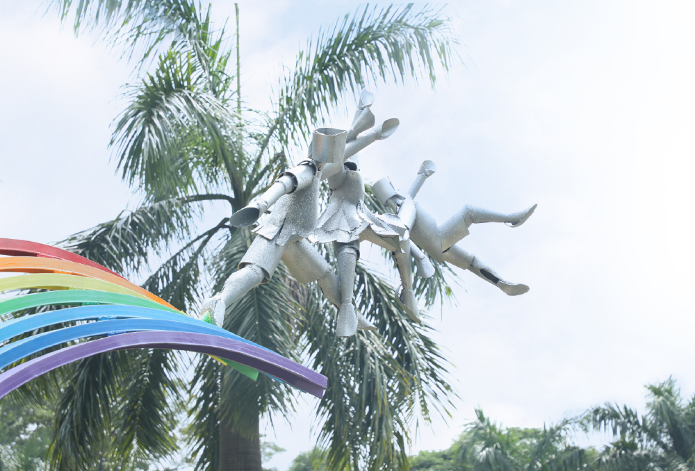 A metal sculpture of children springing from a rainbow at the park entrance.