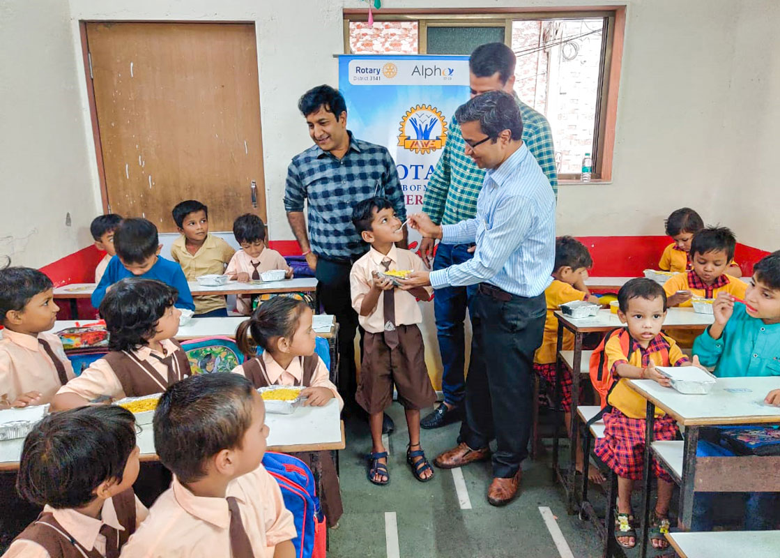 Club president Pankaj Jaiswal feeds a student as project coordinators Sachin Patodia and Devki Nandan Agarwal look on.