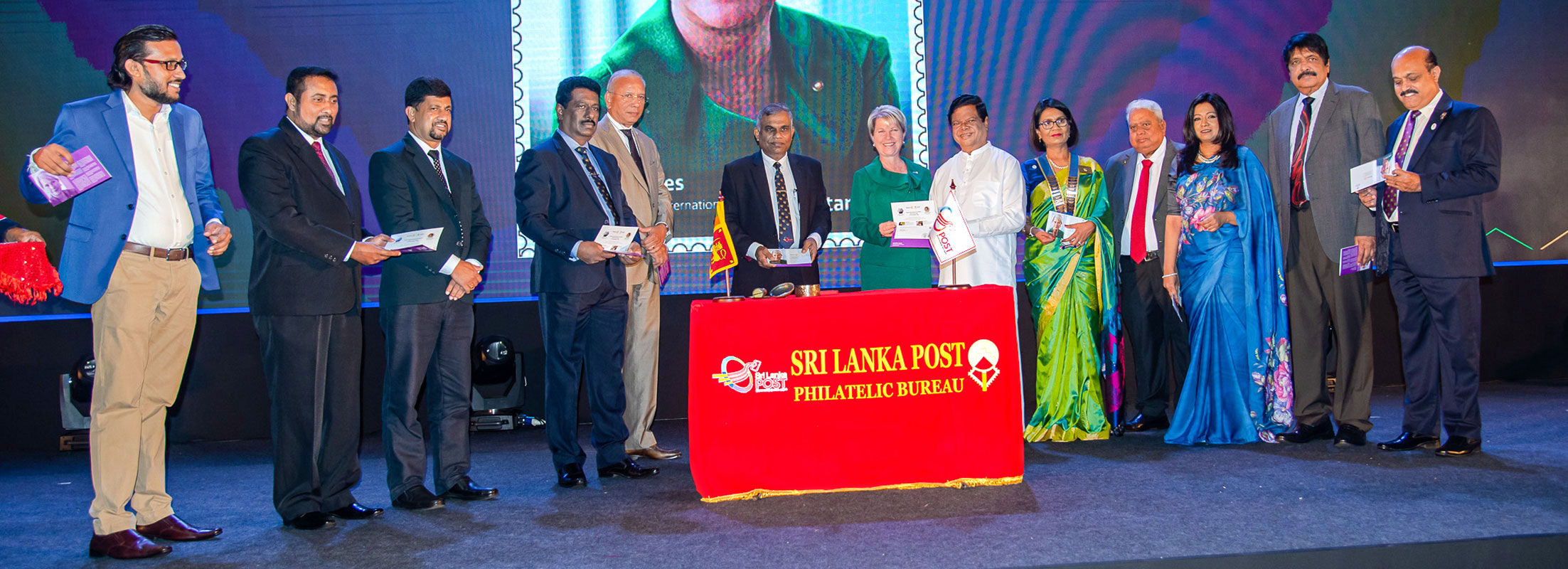 Sri Lankan mass media minister Bandula Gunawardana releasing a postage stamp with a picture of President Jones. Also seen are PRIP Ravindran, DG Pubudu, PDGs Bhashkumar Rajan, Gowri Rajan, Krish Rajendran and Ajith Weerasinghe. 
