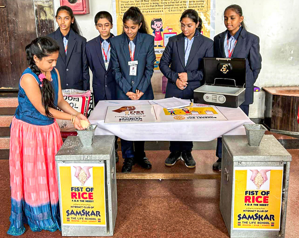 Members of Interact Club of Samskar-the Life School watch as a child donates rice for Project Fist of Rice.