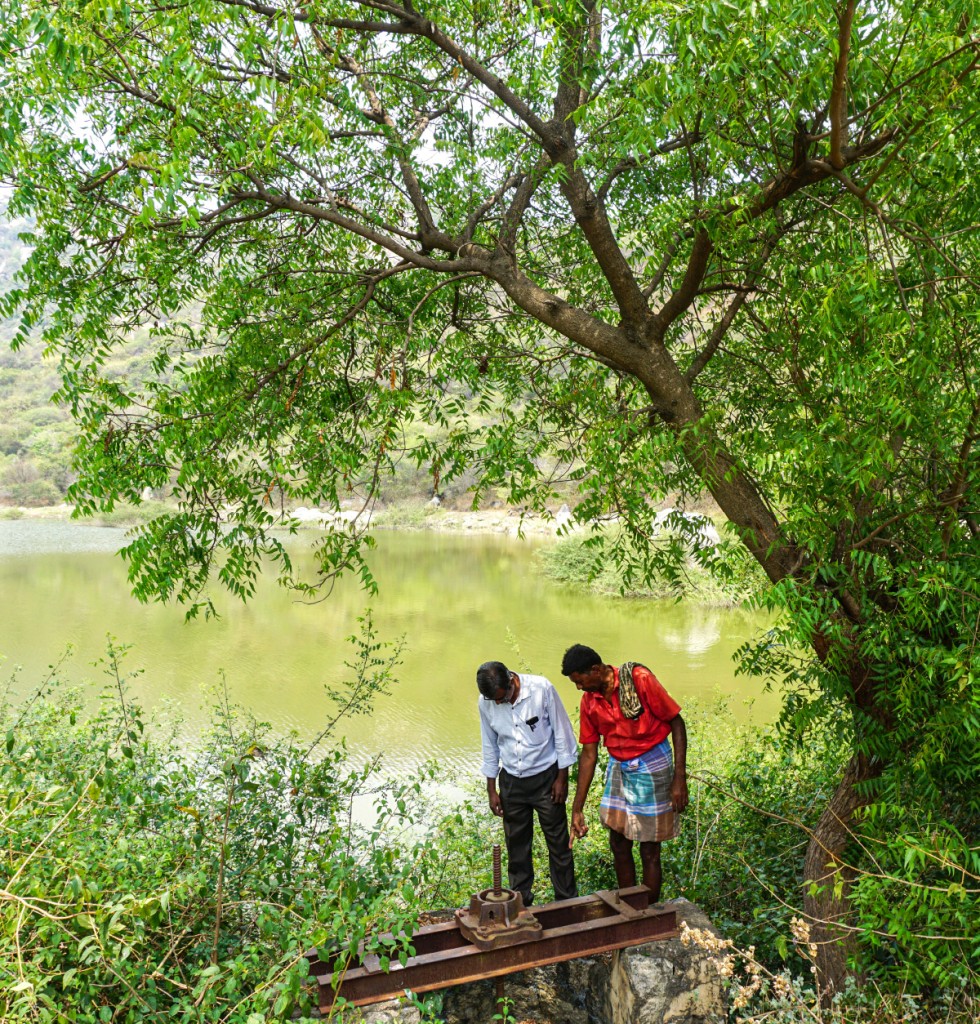 RC Madras Coromandel president Ramesh Ananth examining a sluice gate, along with a villager, near the lake desilted and restored by the club with NABARD’s support.