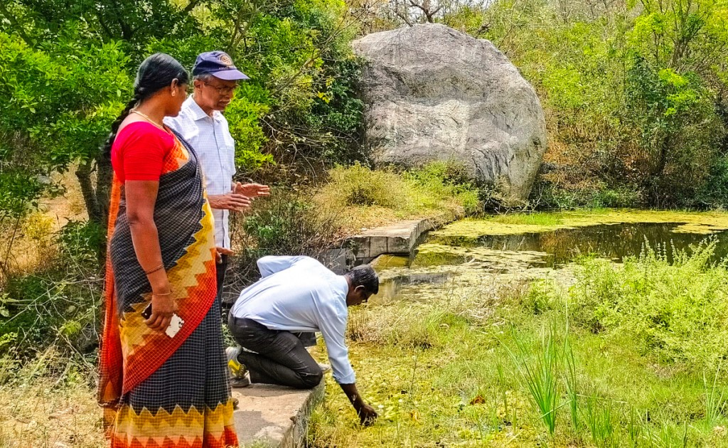 Club president Ramesh Ananth examines the water in a pond as Pramila, a resident of Kuppachiparai village, and Rtn R Sridhar look on.